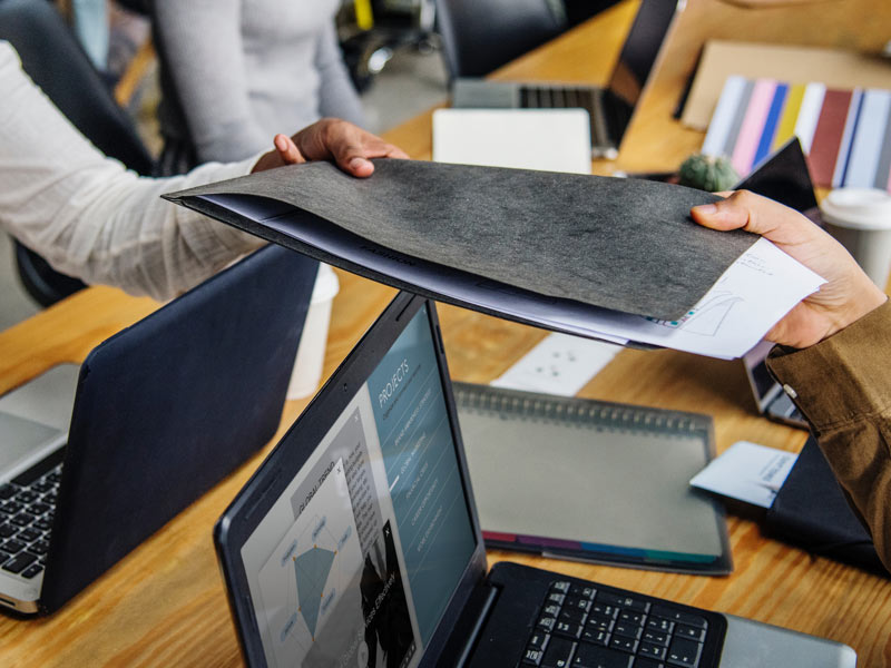 Coworker passing a folder to another coworker