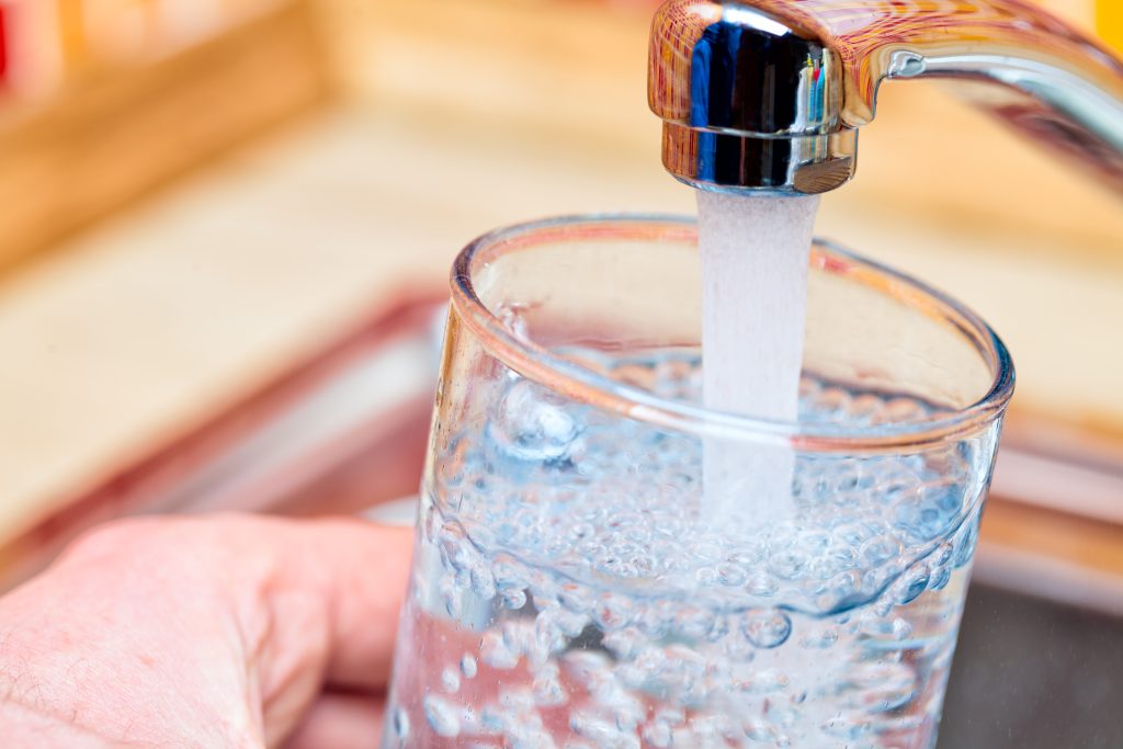 Point of view shot of a person pouring a glass of fresh water from a kitchen faucet